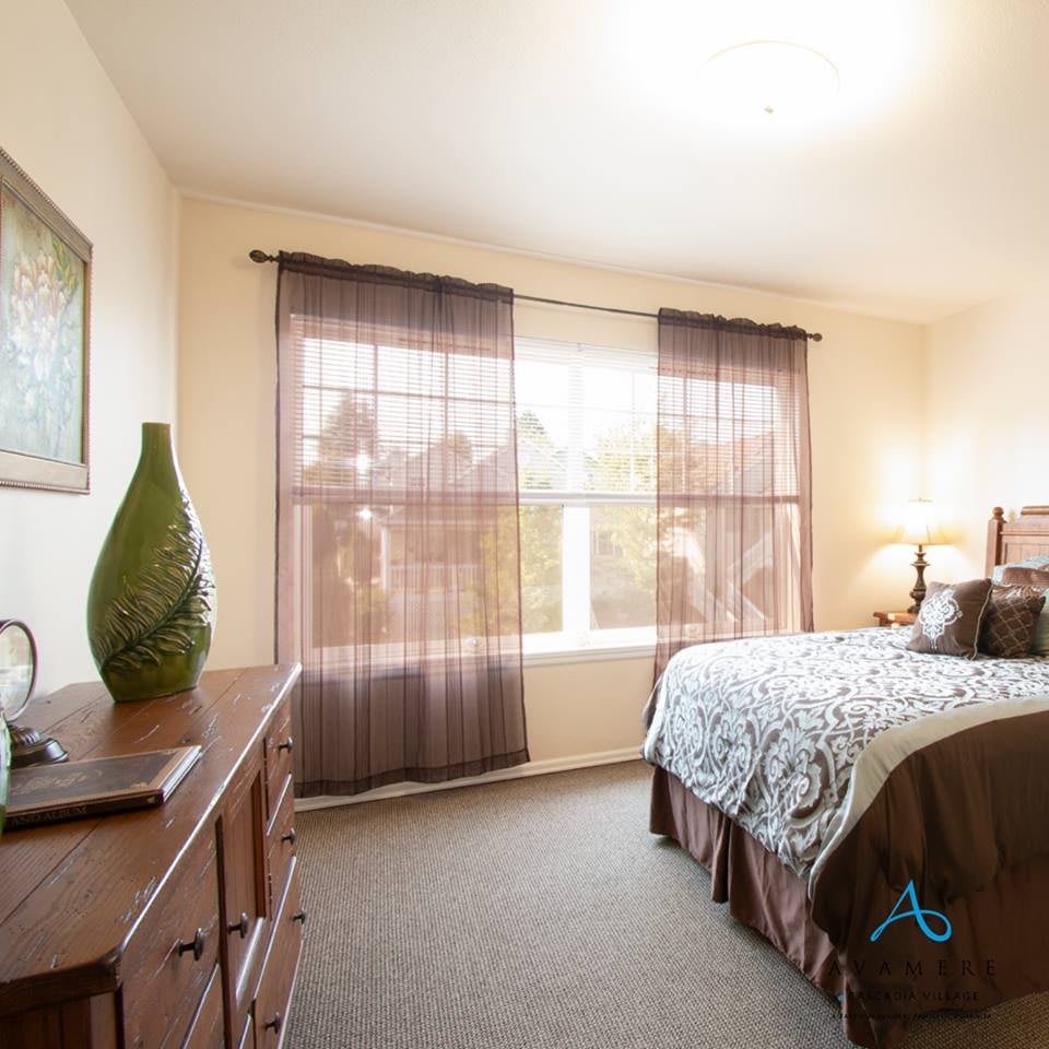 A cozy bedroom with natural light from a large window and stylish decor.