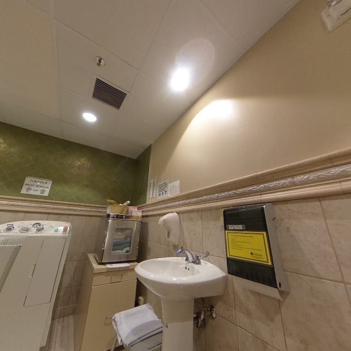 A tiled bathroom with a sink, mirror, and light fixtures.