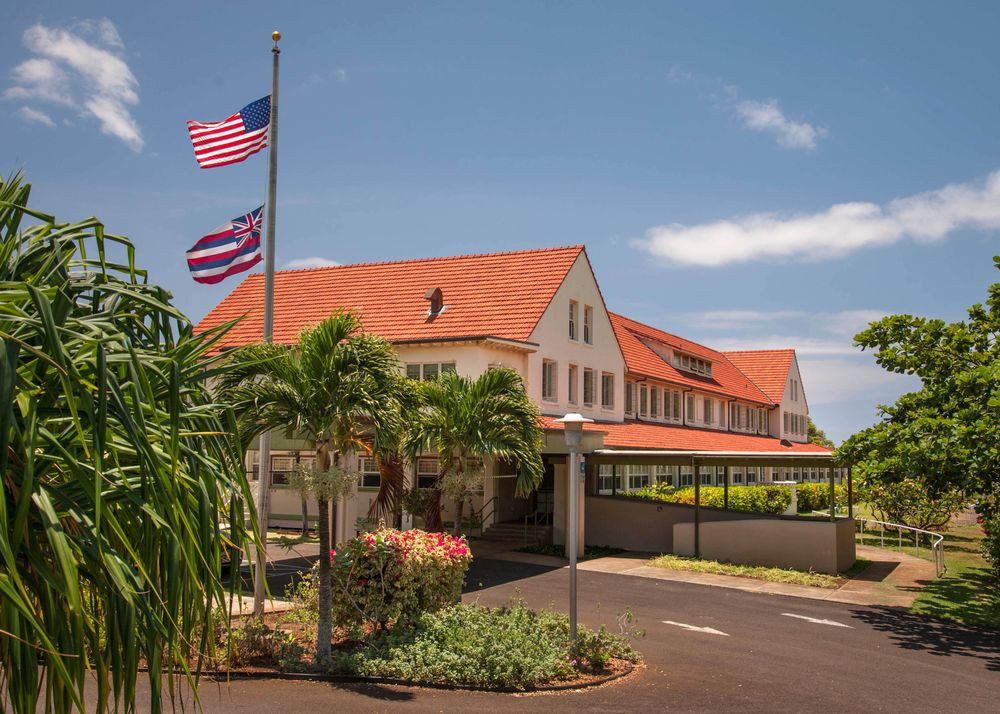 A tropical building with a red roof and American flag on display under a clear sky.