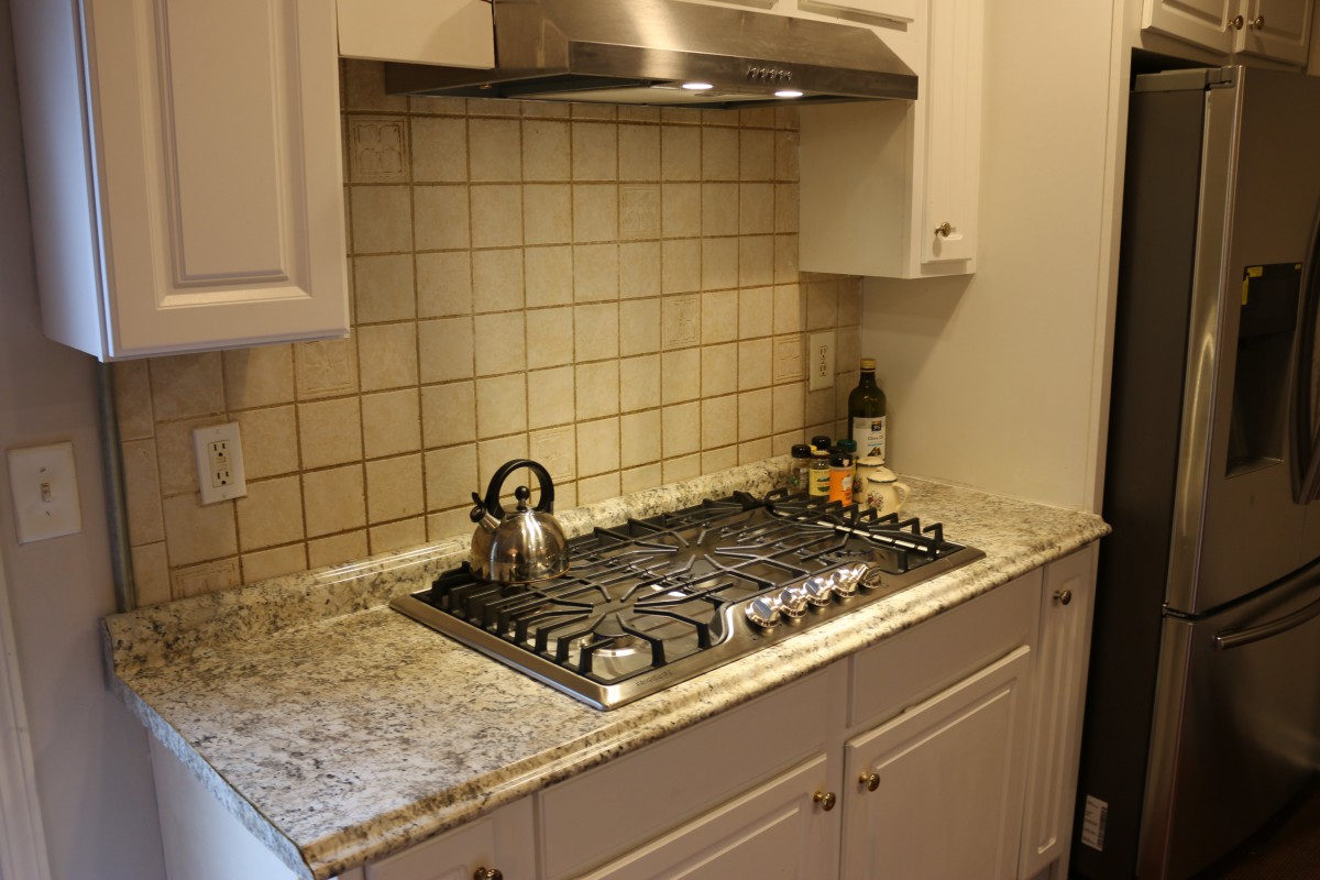 A kitchen with a gas stove and tiled backsplash.