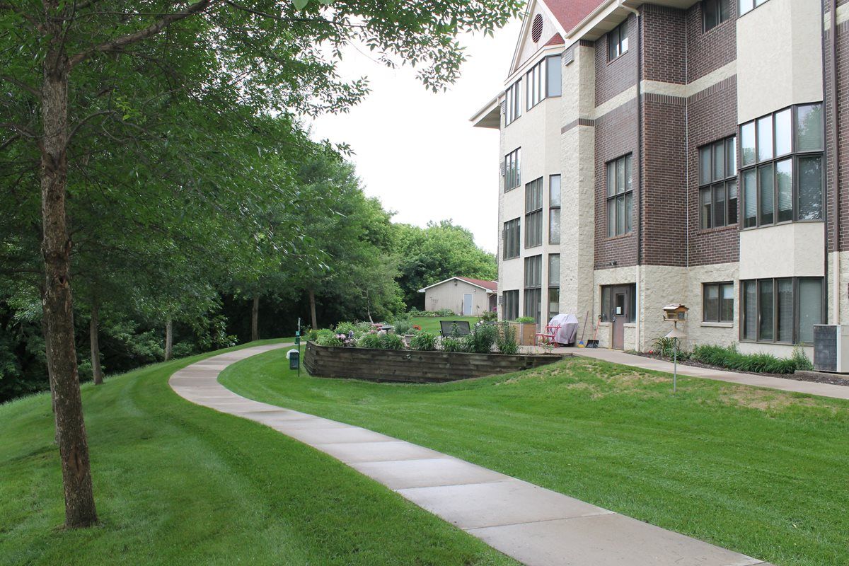 A scenic view of a building with a curved pathway and lush greenery.
