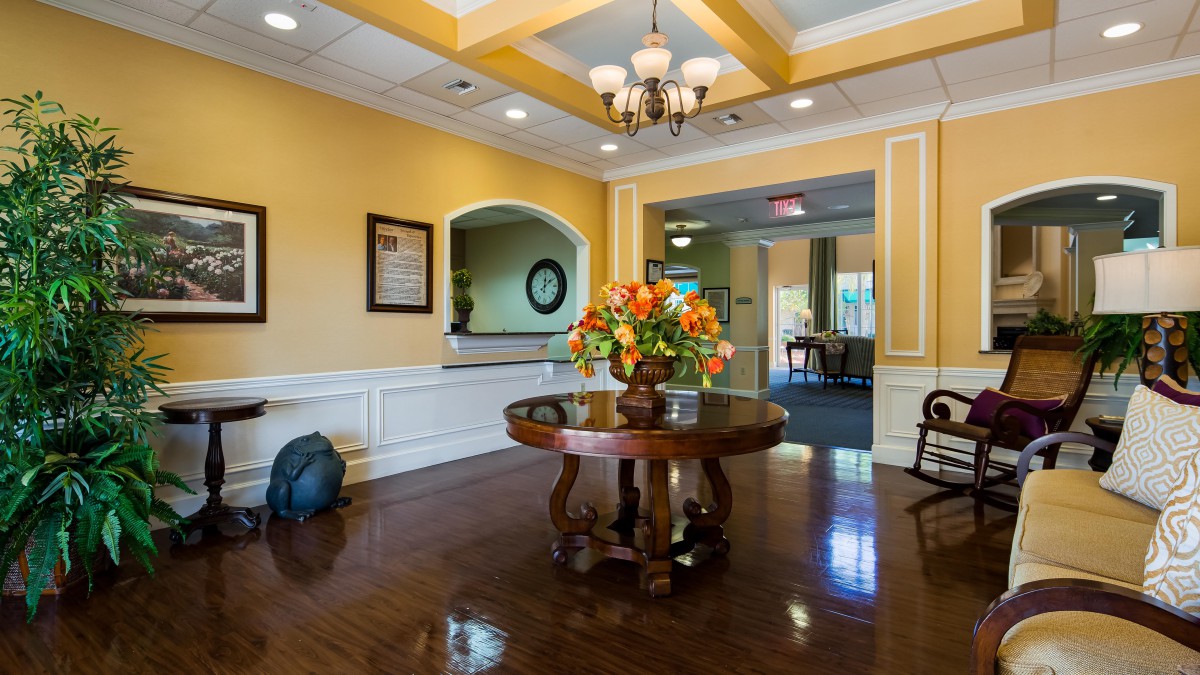 A well-decorated lobby area with a wooden table and floral centerpiece under a chandelier.