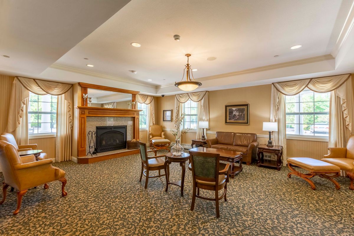 A cozy living room with a fireplace, seating area, and chandelier.