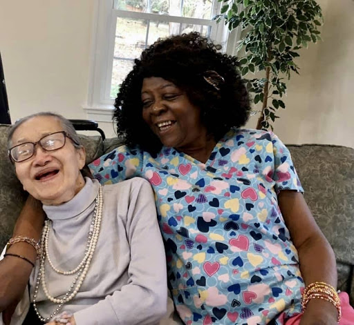 A joyful moment shared between an elderly resident and her caregiver, capturing the essence of companionship and care.
