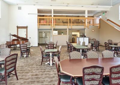 A spacious dining area with multiple tables and chairs, featuring bright lighting and a loft overhead.