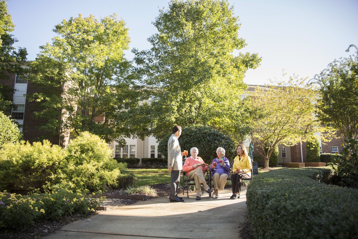 A group of seniors enjoying a conversation in a beautiful garden setting.