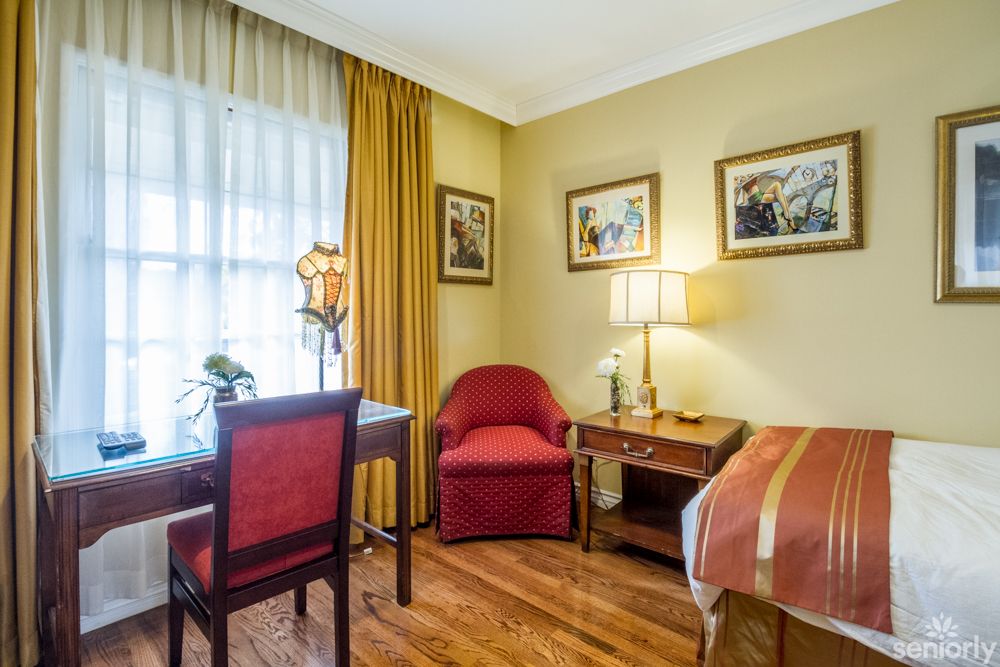 A cozy hotel room with classic decor, featuring a bed, desk, and seating area.