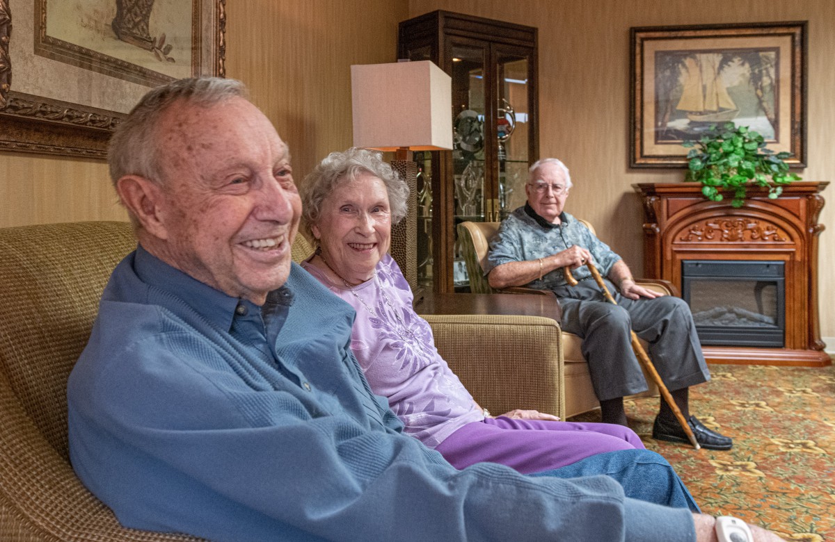 A group of elderly individuals sitting together indoors, smiling and enjoying their time.