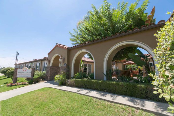 A building with arched entrances surrounded by a well-maintained garden and lawn.