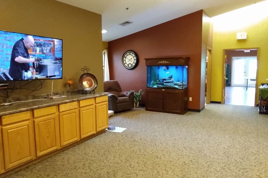 A cozy living room with a television, fish tank, and armchair.