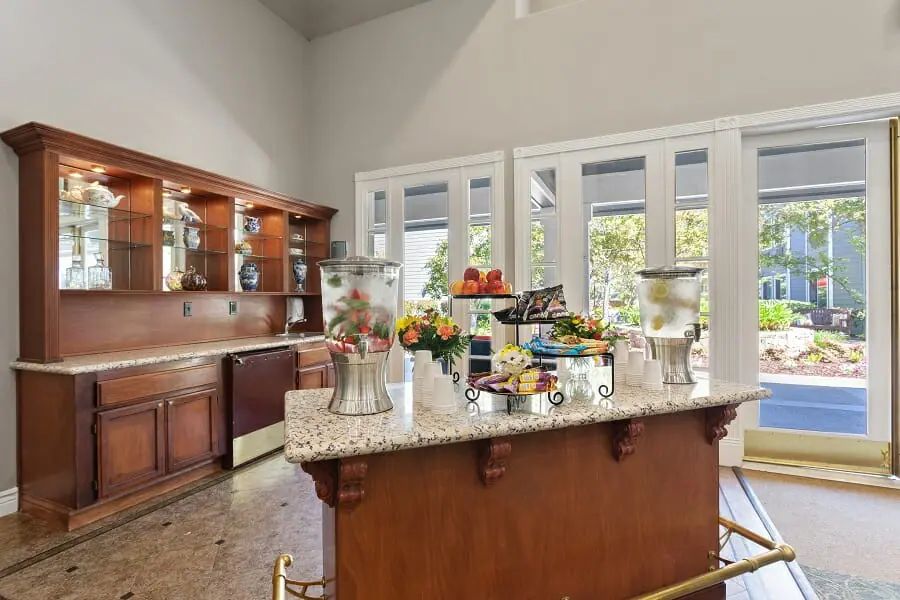 A spacious kitchen with wooden cabinets, a granite island counter, and bright natural lighting from large windows.