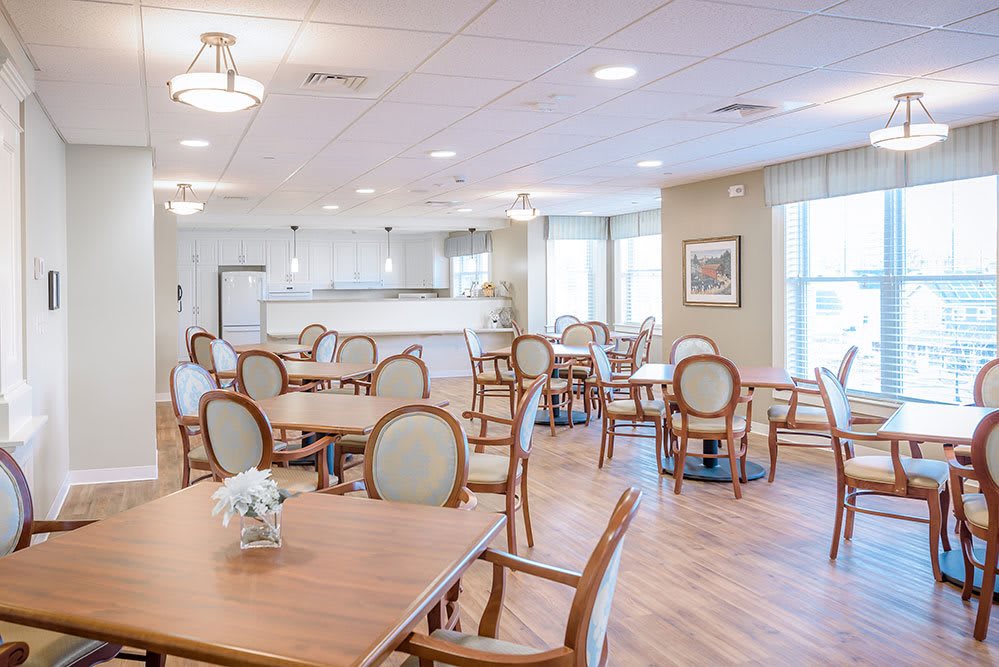 A modern and bright dining area with neatly arranged tables and chairs, featuring large windows.