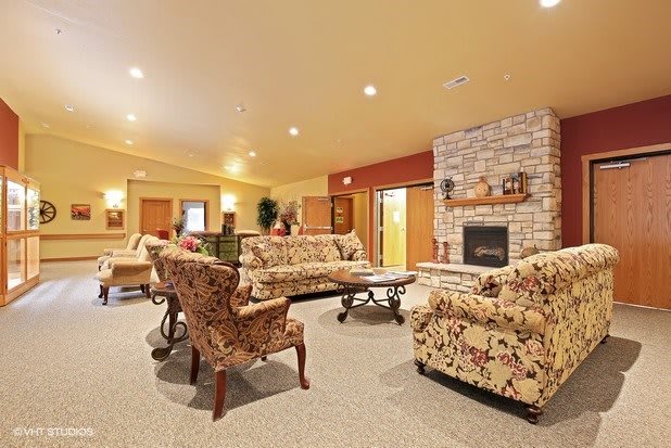 A cozy living room with floral-patterned furniture and a stone fireplace.