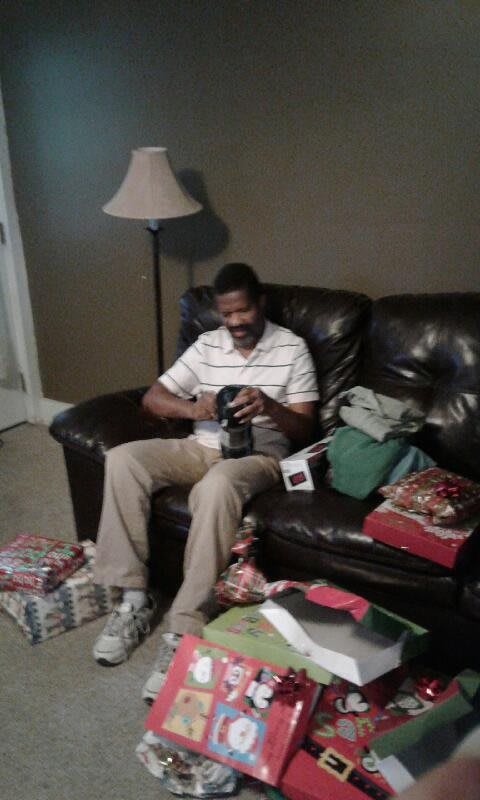 A person sitting on a sofa unwrapping gifts in a living room.