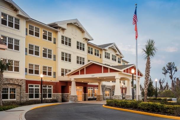 A modern hotel building with an entrance canopy and an American flag flying outside.