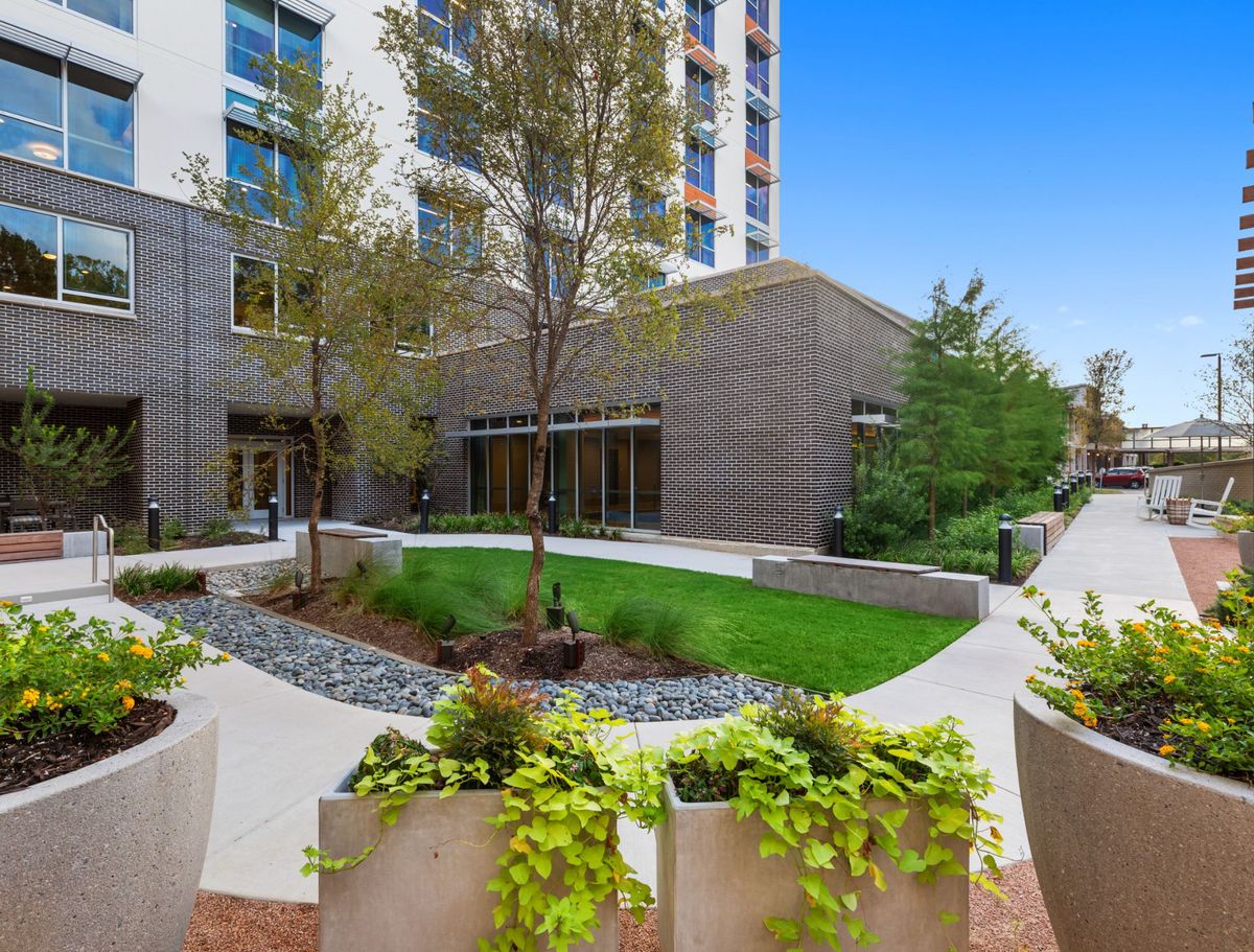 A modern apartment complex featuring lush greenery and a well-maintained outdoor courtyard.