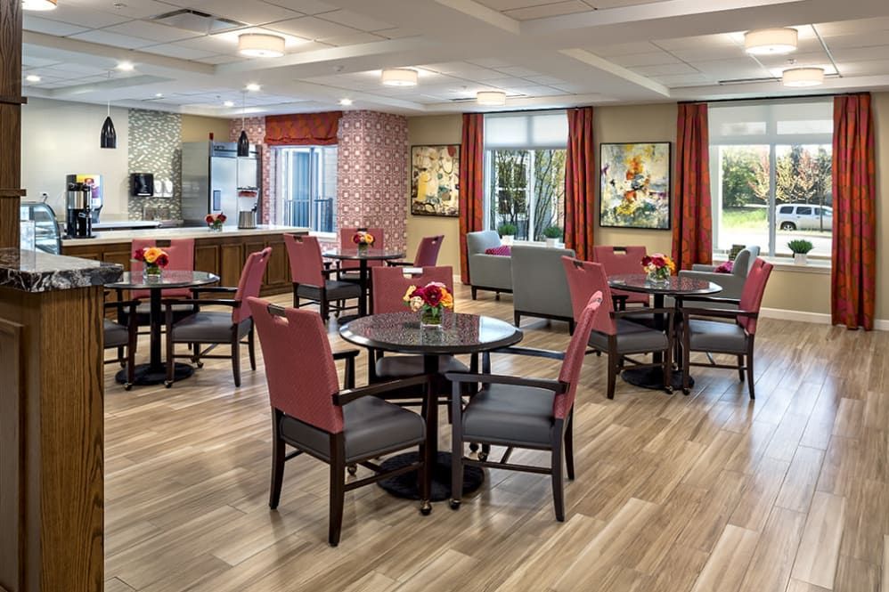 A modern dining area with neatly arranged tables and chairs, featuring stylish decor and large windows.