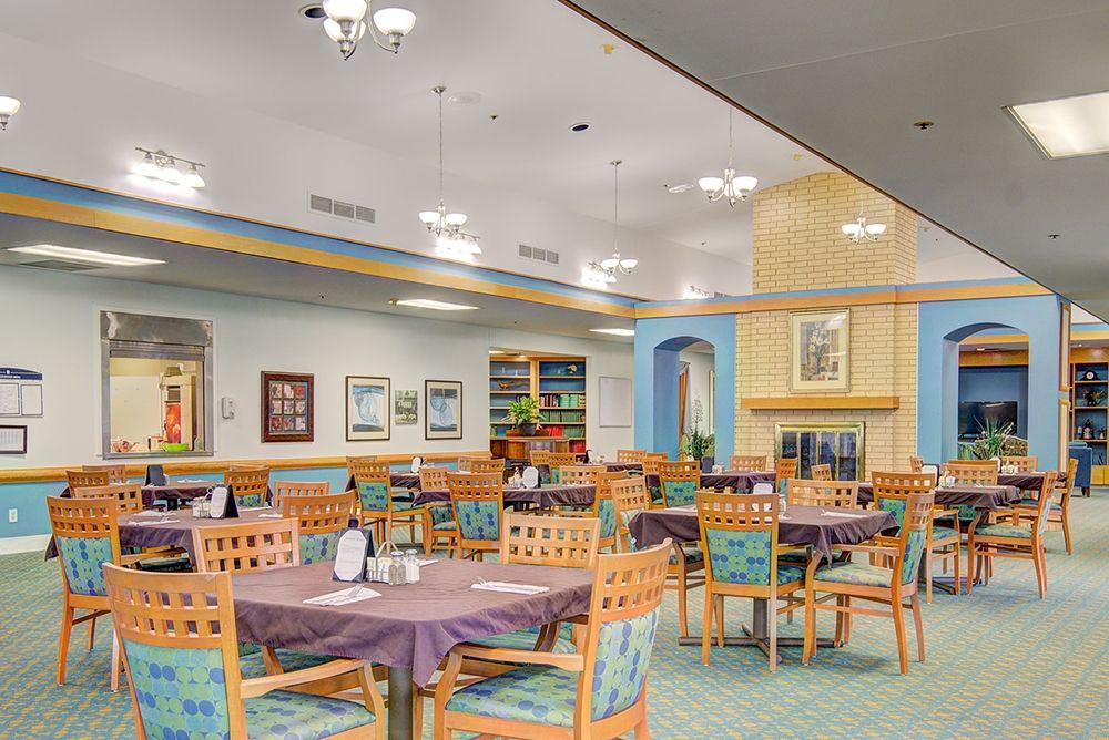 A cozy dining area with neatly arranged tables and chairs, warm lighting, and tasteful decor.