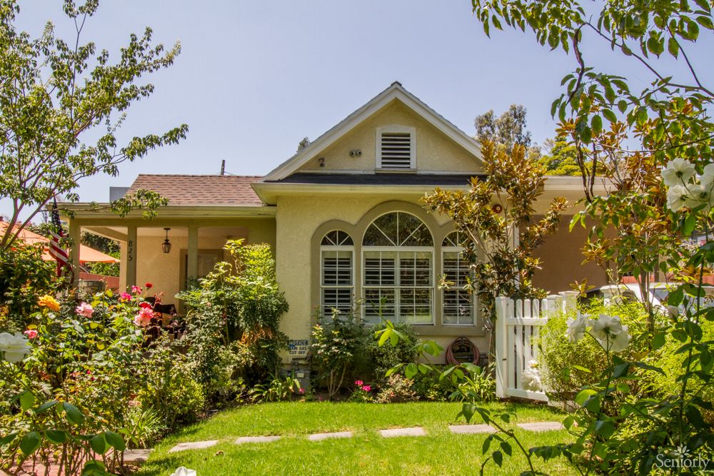 A charming house with a well-maintained garden and lush greenery.