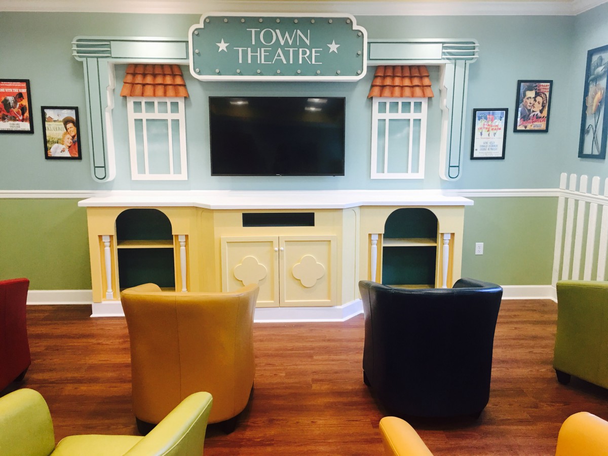 A cozy theater-themed seating area with a large TV screen and comfortable chairs.