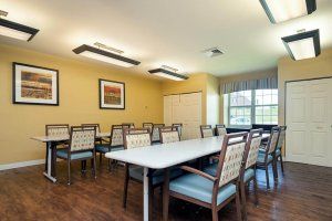 A well-lit dining room with several tables and chairs, featuring framed artwork on the walls.