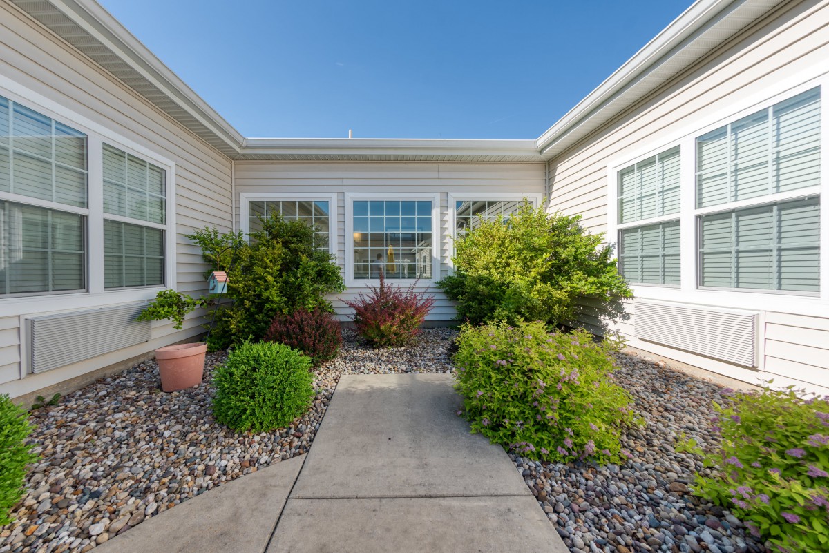 A neatly landscaped courtyard with plants and a pathway leading to the house.