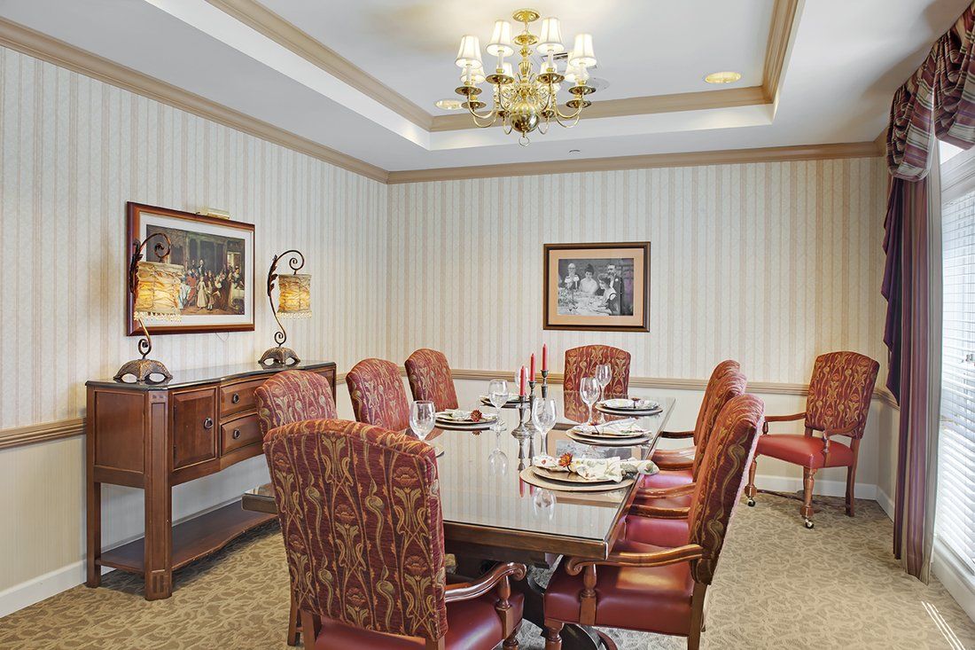 A formal dining room with a large table, upholstered chairs, and elegant decor.