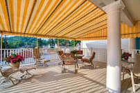 A cozy outdoor patio with a striped awning providing shade over a seating area.