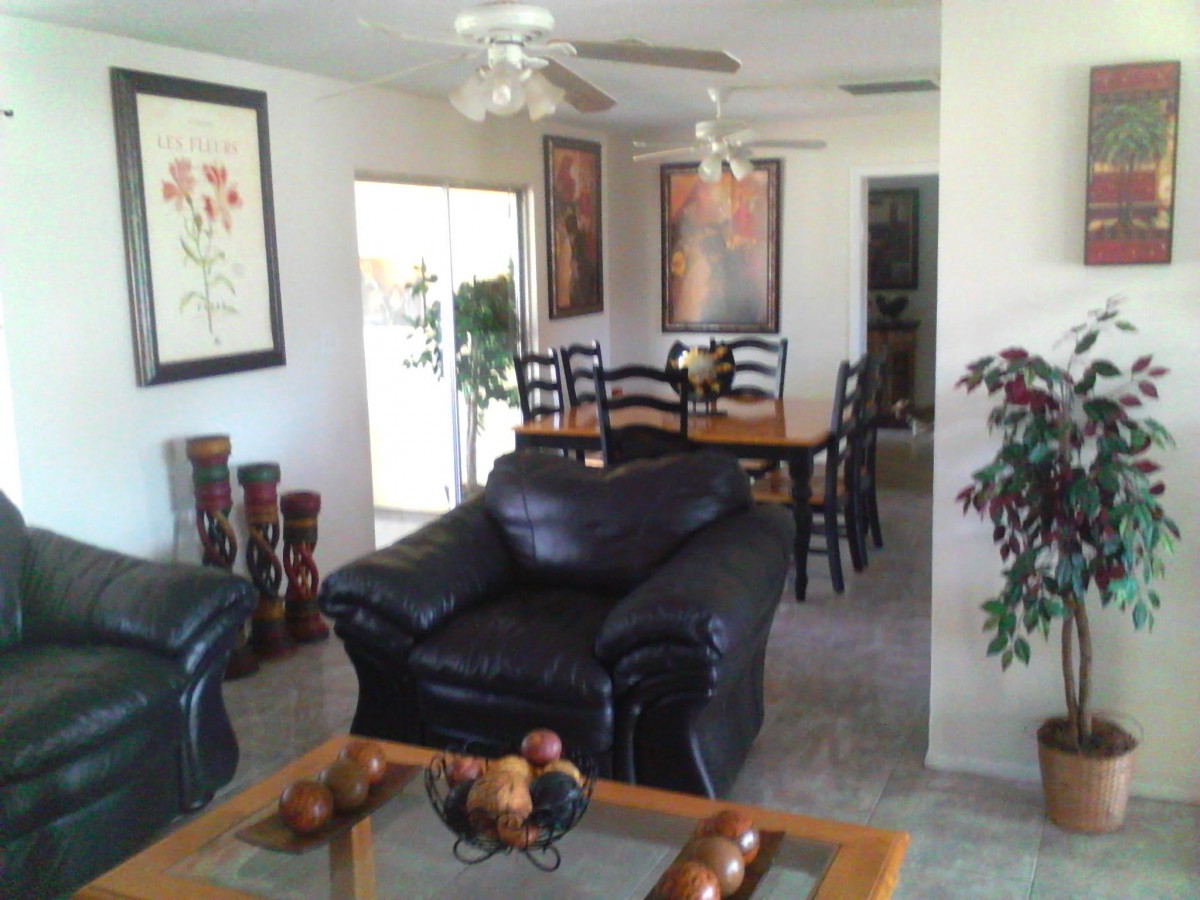 A cozy living room with black leather furniture and a dining area adorned with artwork.