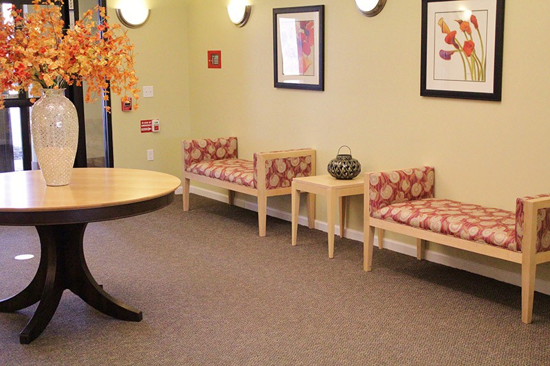 A well-arranged waiting room with patterned chairs, framed art, and a decorative vase on a table.