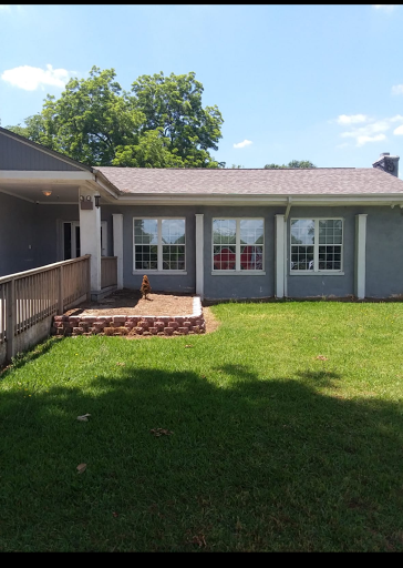 A charming view of the house's backyard with a patio and lush green grass.