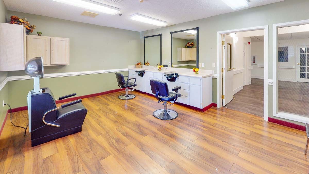An empty salon with mirrors and styling chairs on a hardwood floor.