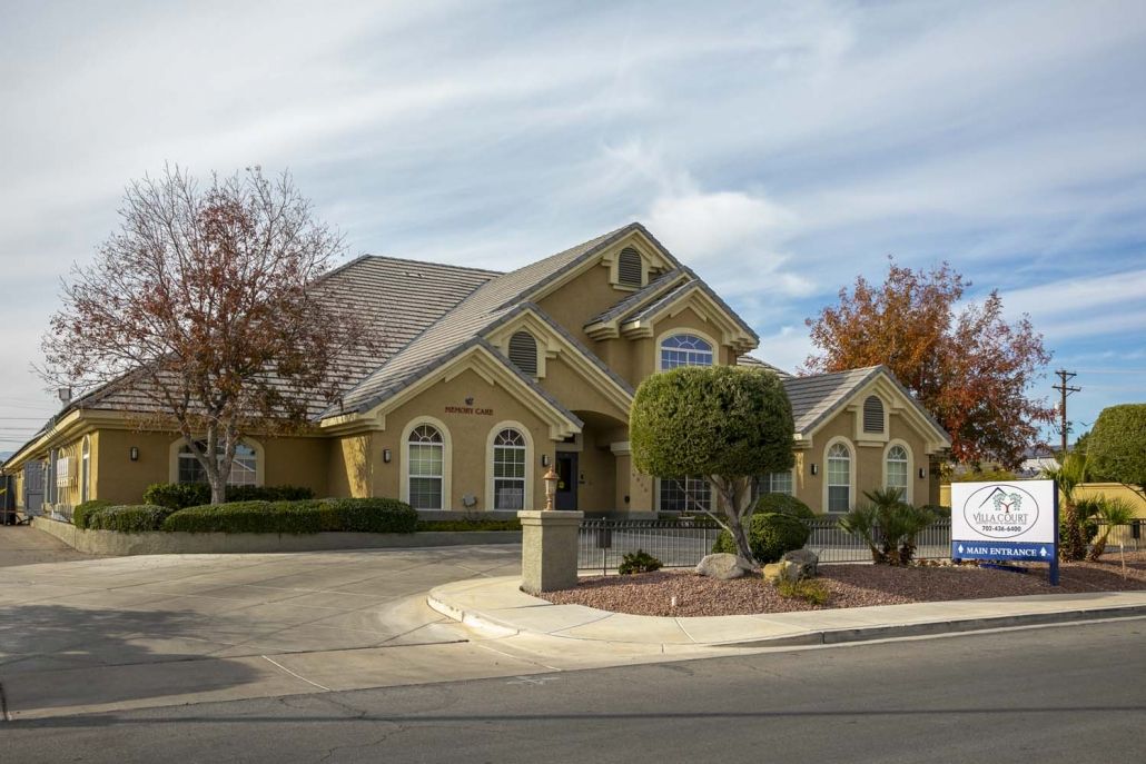 A suburban residential house with a landscaped front yard and cloudy skies above.