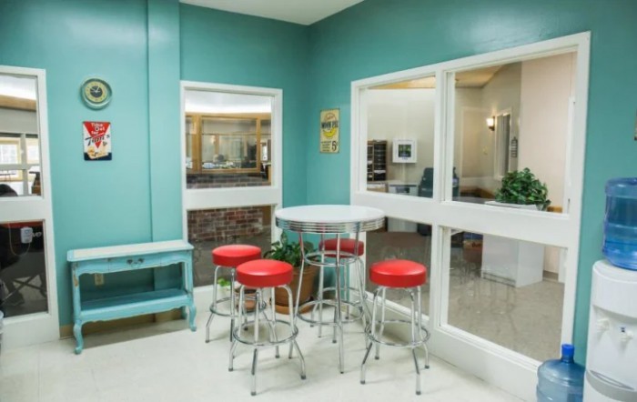 A retro-style diner with teal walls and red barstools.
