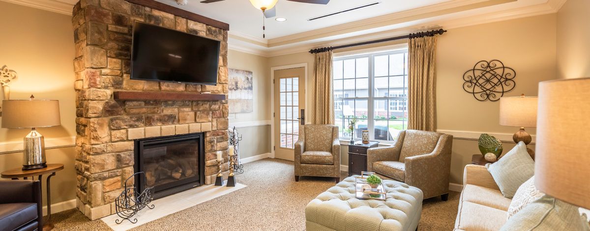 A cozy living room features a stone fireplace, flat-screen TV, and plush seating.
