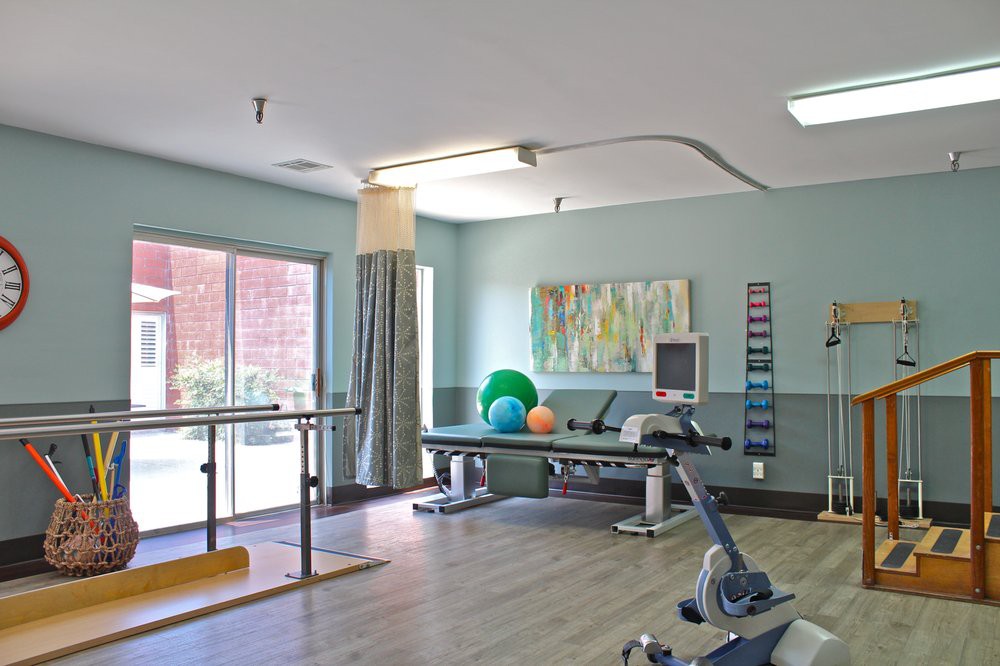 A spacious physical therapy room equipped with various exercise tools and apparatuses for rehabilitation.