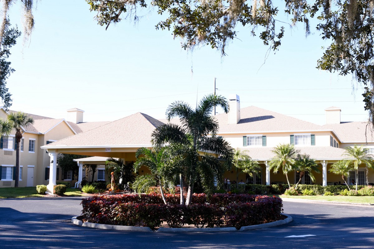 A sunny view of a residential building with palm trees and well-maintained landscaping.