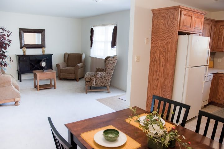 A cozy living space featuring a comfortable armchair, a television, and a dining area with table settings.