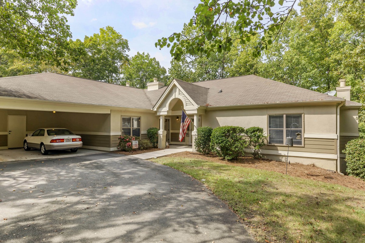 A suburban house with a driveway and garage, surrounded by trees.