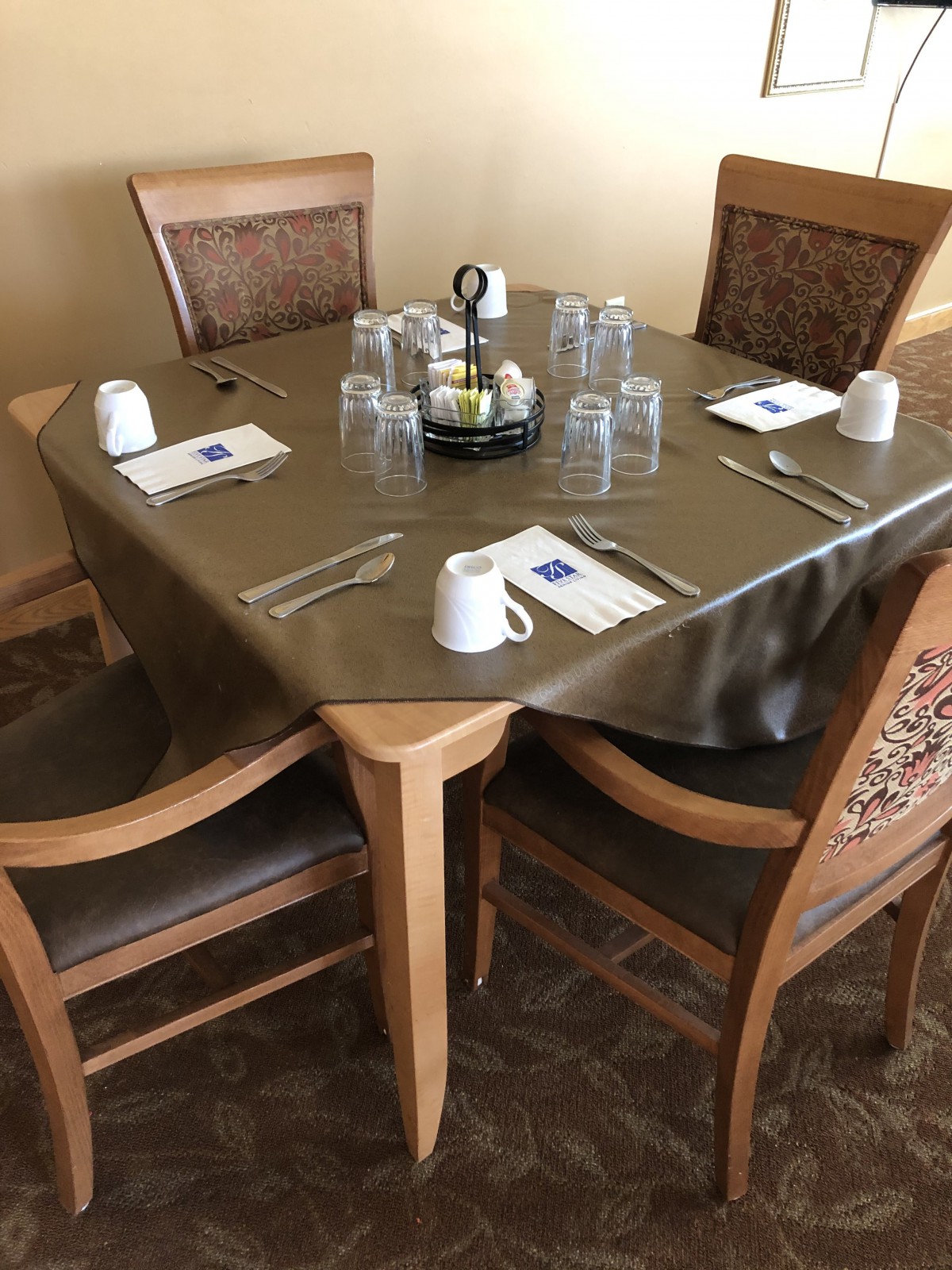 A neatly set dining table with four chairs in a restaurant.