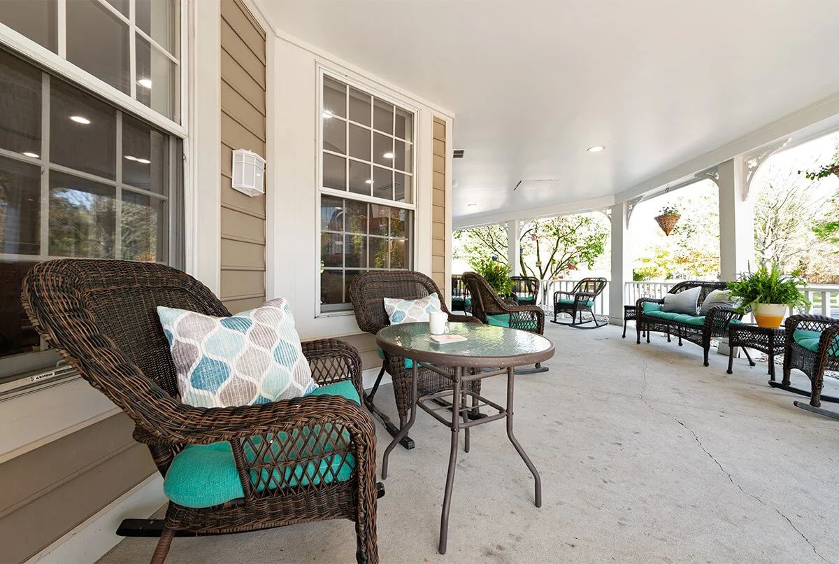 A cozy porch with wicker furniture and colorful pillows, perfect for relaxation.