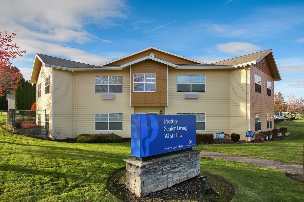 A retirement living facility with a prominent blue sign in front of a well-maintained lawn.