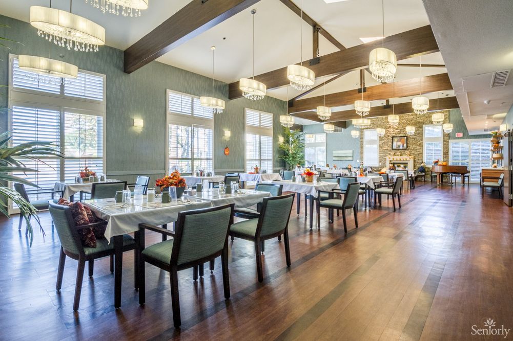 A spacious and elegantly designed dining area with modern lighting fixtures and neatly arranged tables and chairs.