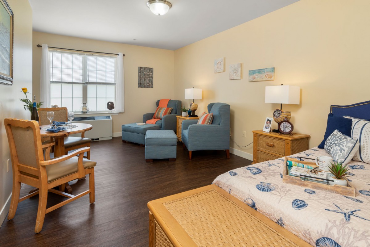 A cozy living space featuring comfortable chairs, a bed, and warm lighting.