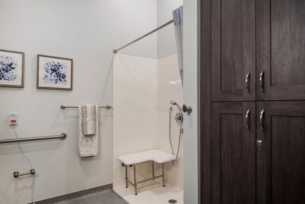 A modern bathroom featuring an accessible shower with a bench and towel racks.