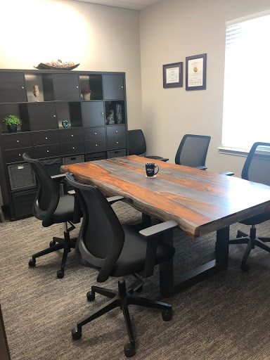 A modern conference room featuring a large wooden table and ergonomic chairs, ready for meetings.