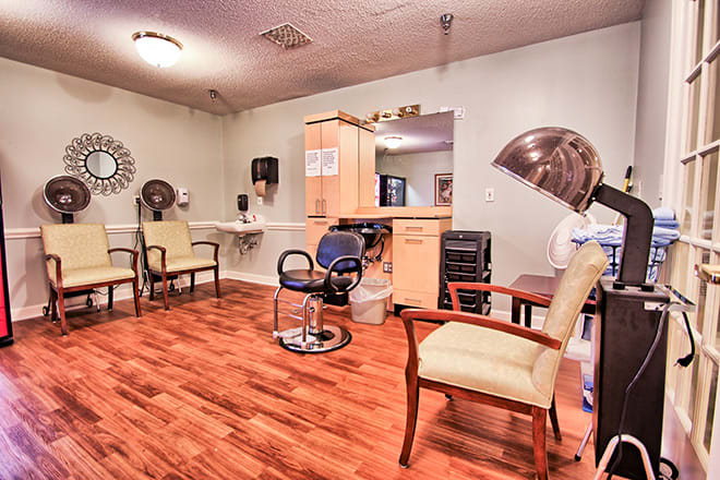 A cozy salon interior featuring styling chairs, mirrors, and hair dryers on a wooden floor.