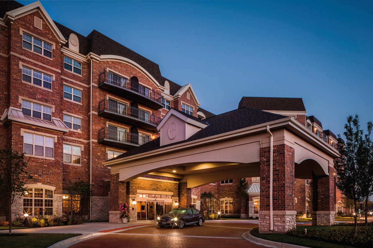 A cozy hotel entrance with a car parked under the canopy during the evening.