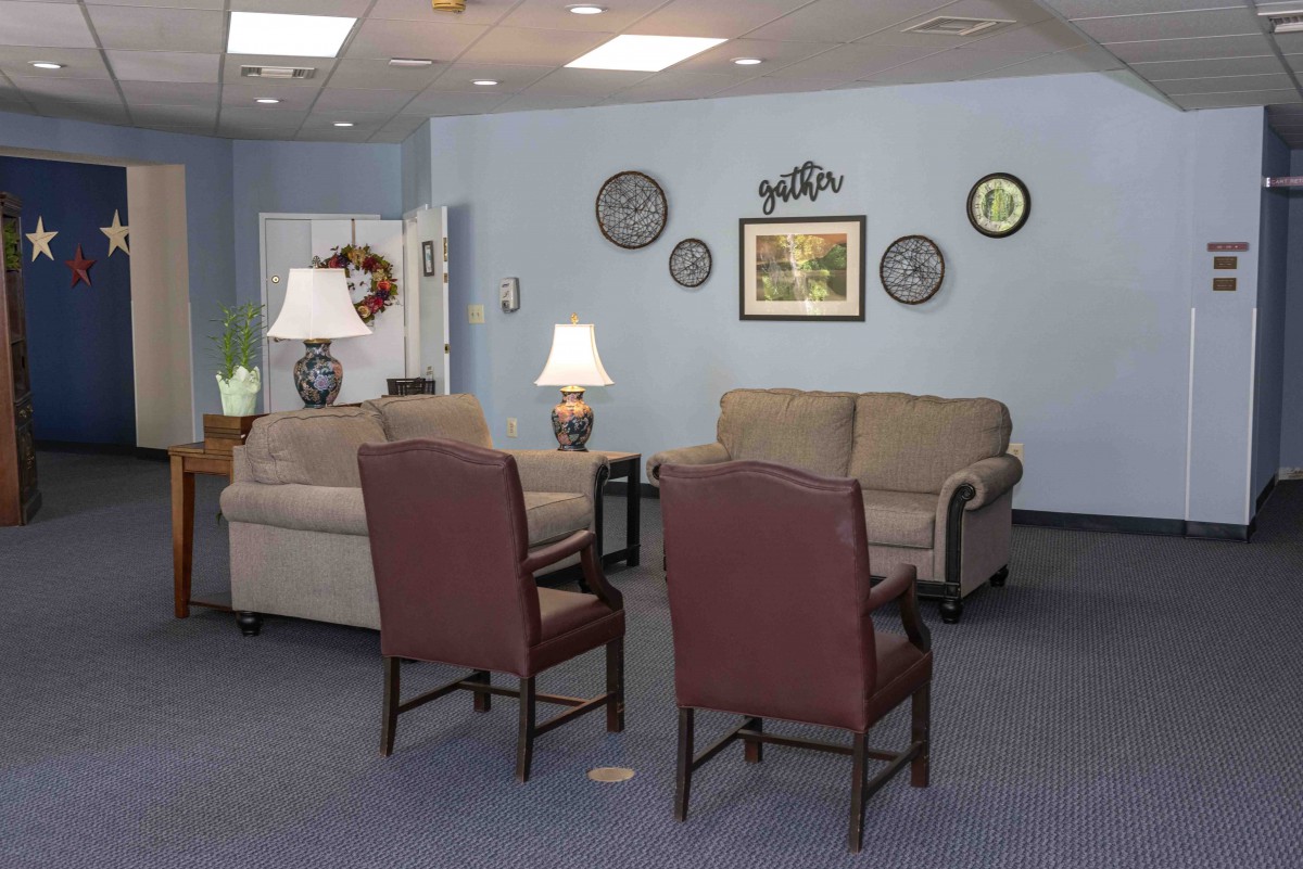 A cozy waiting room with sofas, chairs, and decorative wall art.