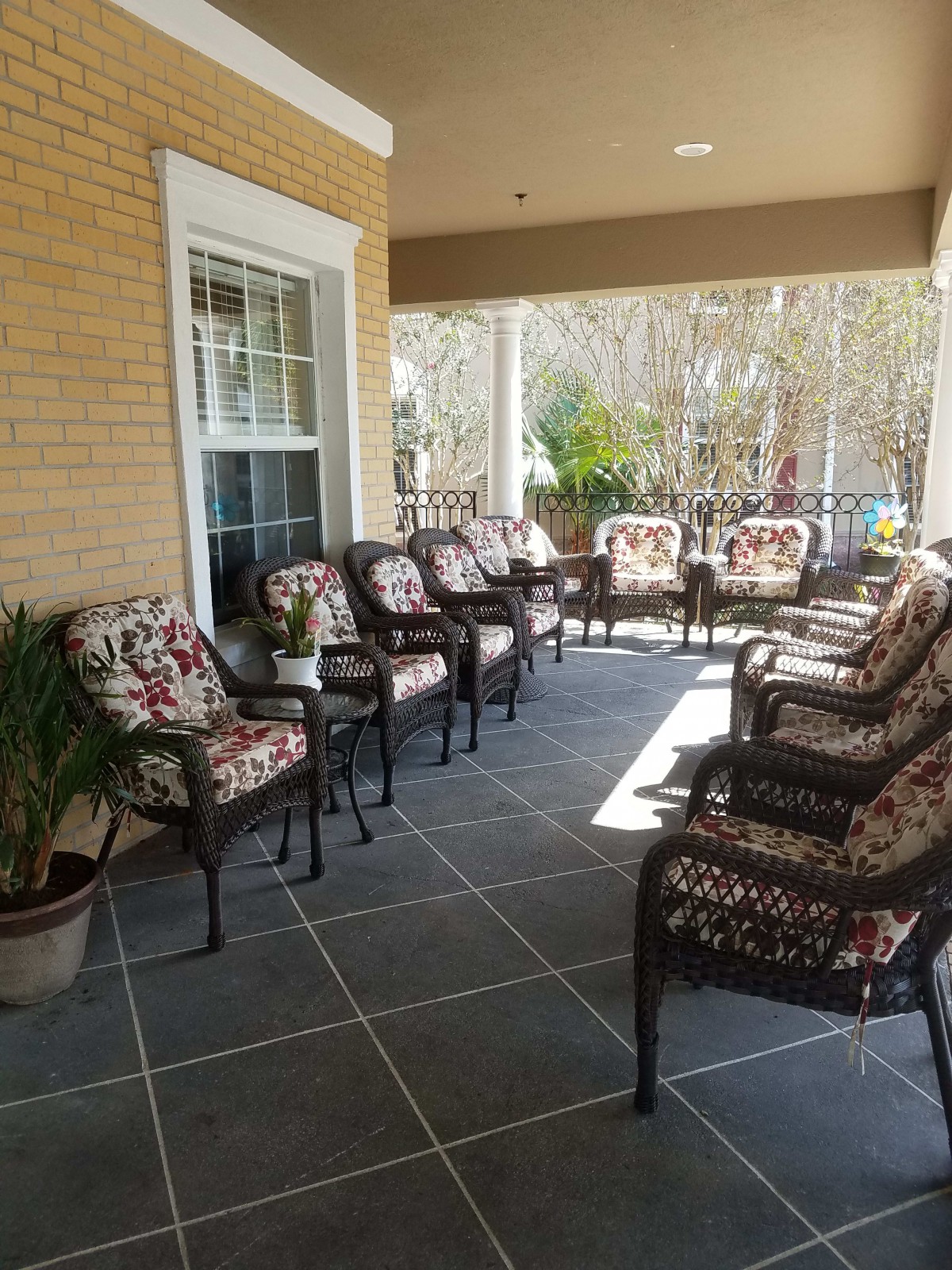 A cozy outdoor patio with wicker chairs and floral cushions, perfect for relaxation.